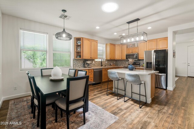 1812 E Parkside Ln E, Phoenix, AZ 85024 - kitchen featuring stainless steel appliances, light brown cabinetry, tasteful backsplash, a kitchen island, and wood finished floors