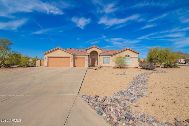 view of front of property featuring a garage, concrete driveway, a tile roof, and stucco siding