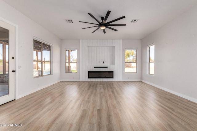 unfurnished living room with visible vents, light wood-style floors, a large fireplace, ceiling fan, and baseboards