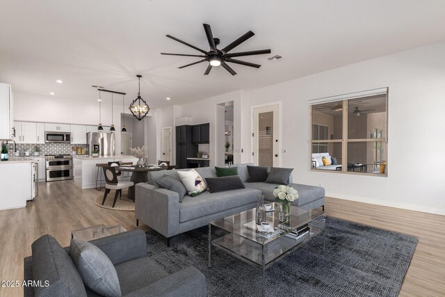 living room with a ceiling fan, recessed lighting, visible vents, and light wood finished floors