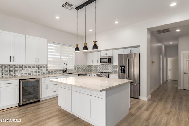 kitchen featuring wine cooler, a sink, a center island, high end appliances, and decorative light fixtures