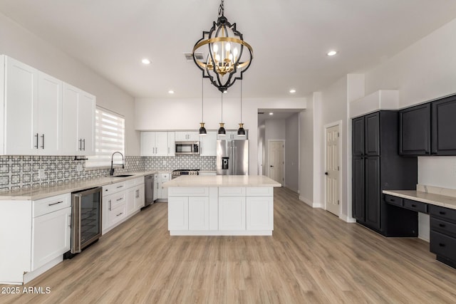 kitchen with stainless steel appliances, wine cooler, hanging light fixtures, and a center island