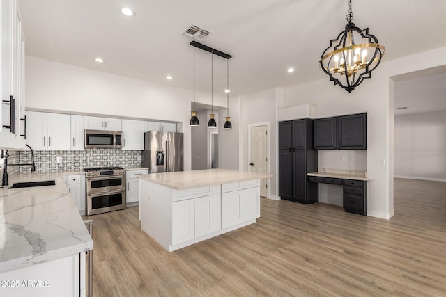 kitchen featuring a sink, white cabinetry, appliances with stainless steel finishes, a center island, and decorative light fixtures