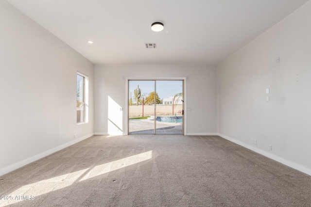 empty room featuring light carpet, visible vents, and baseboards