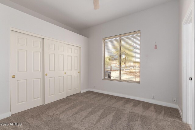 unfurnished bedroom with ceiling fan, a closet, baseboards, and carpet flooring