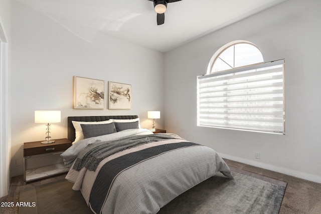 bedroom featuring a ceiling fan, dark colored carpet, multiple windows, and baseboards