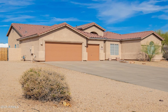view of front of home with a garage, fence, a tile roof, and stucco siding