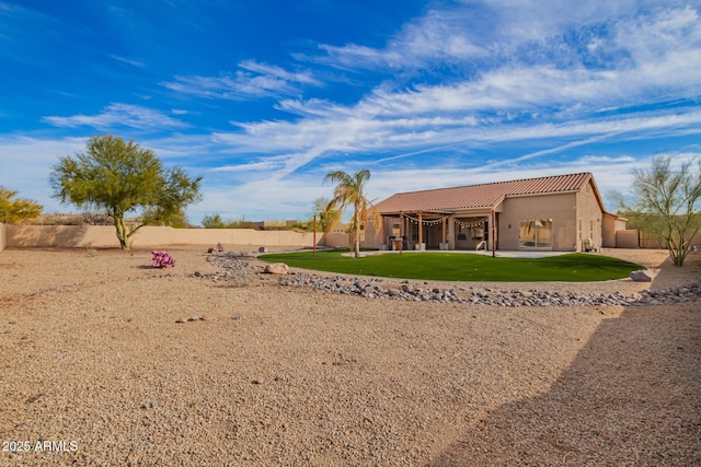 rear view of house with a patio, a fenced backyard, a tile roof, a yard, and stucco siding
