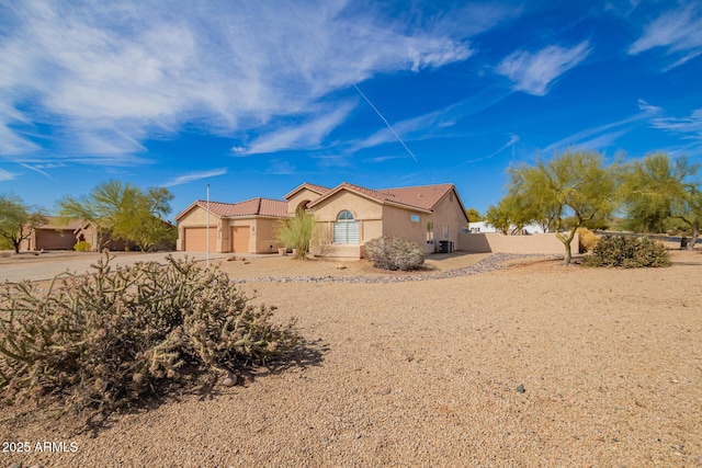 view of front of home with driveway, an attached garage, a tile roof, and stucco siding