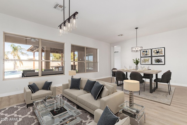 living room with wood finished floors, visible vents, and baseboards