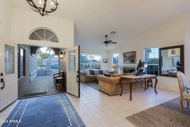 tiled living room with high vaulted ceiling and ceiling fan with notable chandelier