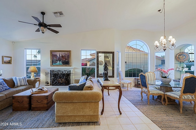 tiled living room with ceiling fan with notable chandelier, a healthy amount of sunlight, and lofted ceiling