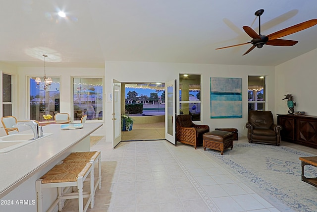 tiled living room with ceiling fan with notable chandelier and sink