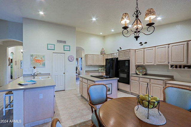 kitchen featuring black appliances, a notable chandelier, a high ceiling, a center island, and hanging light fixtures