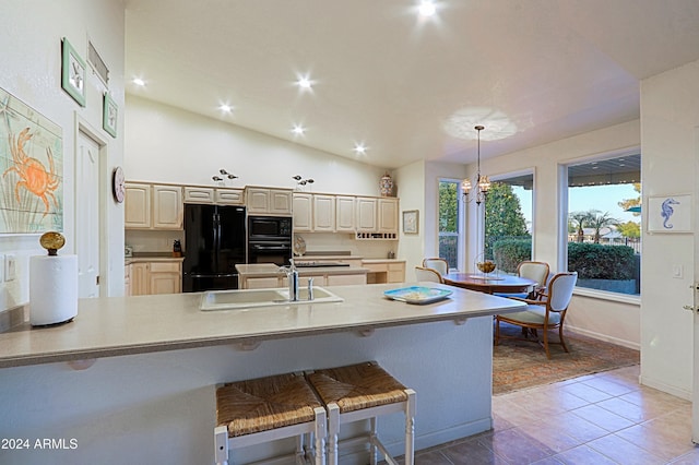 kitchen featuring sink, pendant lighting, lofted ceiling, a breakfast bar, and black appliances