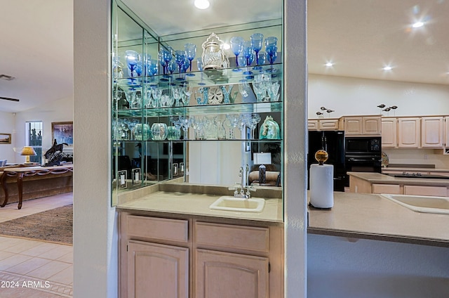 bar with black appliances, tile patterned flooring, lofted ceiling, and sink