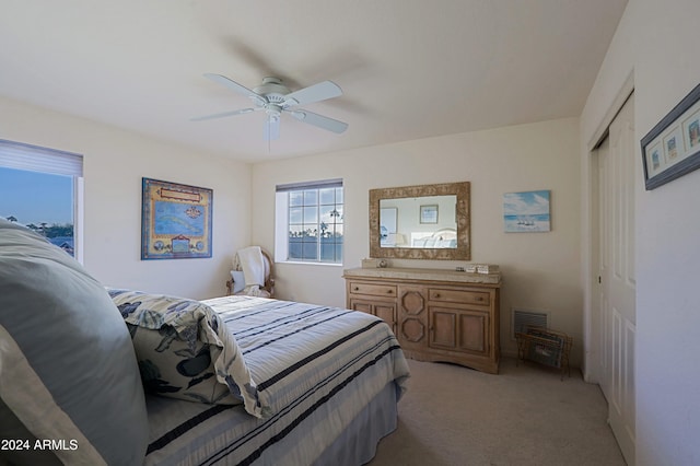 bedroom with ceiling fan, a closet, and light colored carpet