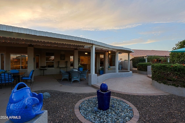 back house at dusk featuring a patio