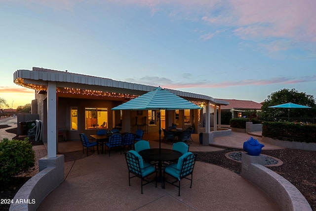 back house at dusk featuring a patio