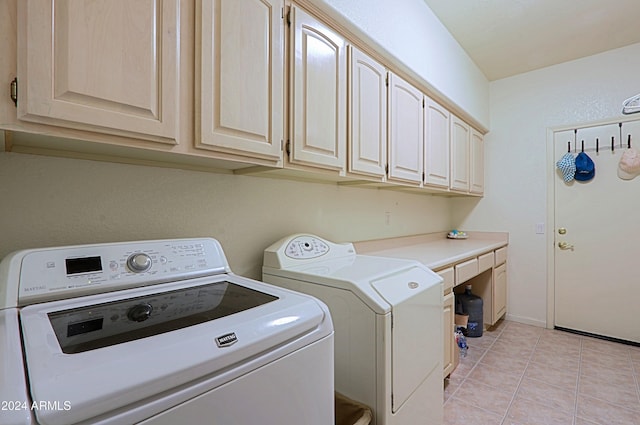 laundry area featuring washing machine and dryer, light tile patterned floors, and cabinets