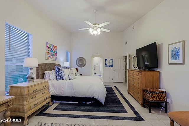 tiled bedroom with a towering ceiling and ceiling fan