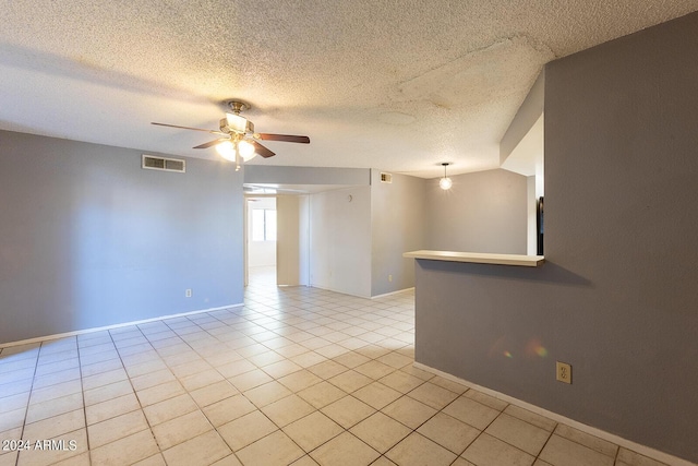 unfurnished room with ceiling fan, light tile patterned floors, a textured ceiling, visible vents, and baseboards