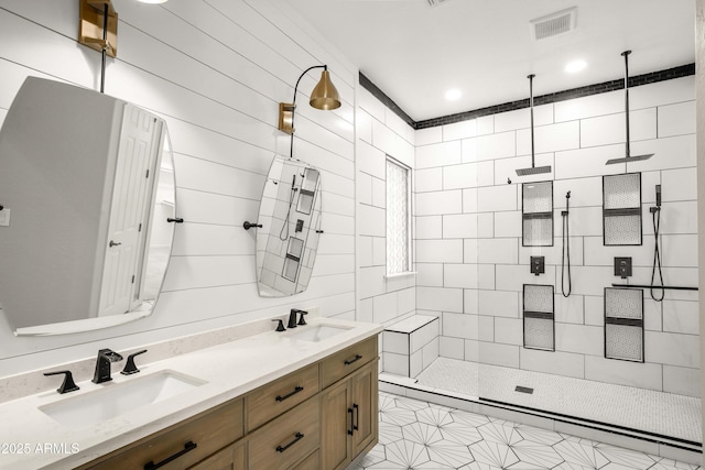 full bathroom with tiled shower, double vanity, and tile patterned flooring