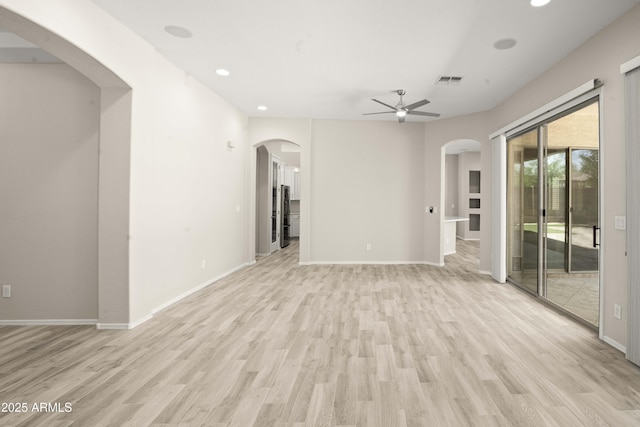unfurnished living room with arched walkways, light wood finished floors, ceiling fan, and recessed lighting
