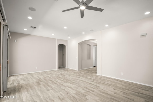 empty room with arched walkways, ceiling fan, light wood finished floors, recessed lighting, and baseboards
