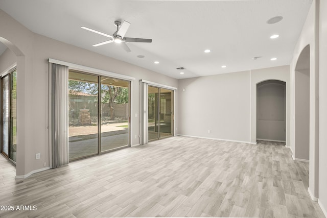 unfurnished living room with arched walkways, a ceiling fan, light wood-style flooring, baseboards, and recessed lighting