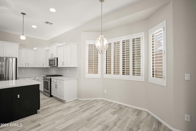 kitchen featuring appliances with stainless steel finishes, light countertops, light wood finished floors, hanging light fixtures, and recessed lighting