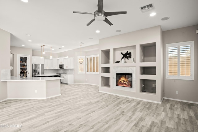 unfurnished living room with a sink, light wood-style flooring, a ceiling fan, baseboards, and recessed lighting