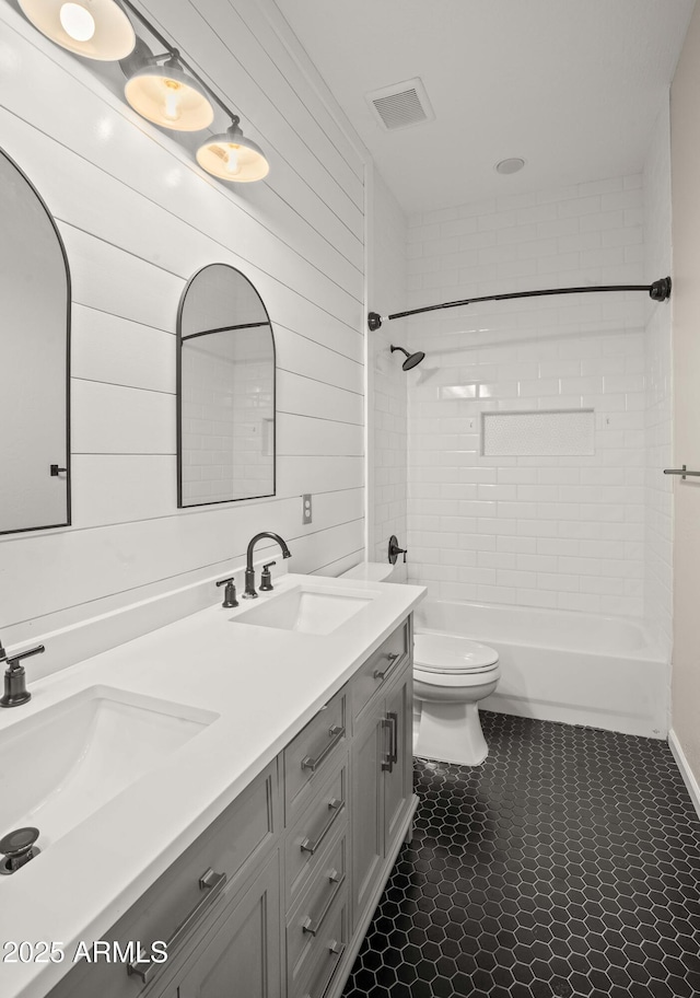 bathroom featuring toilet, double vanity, shower / bathtub combination, and tile patterned floors