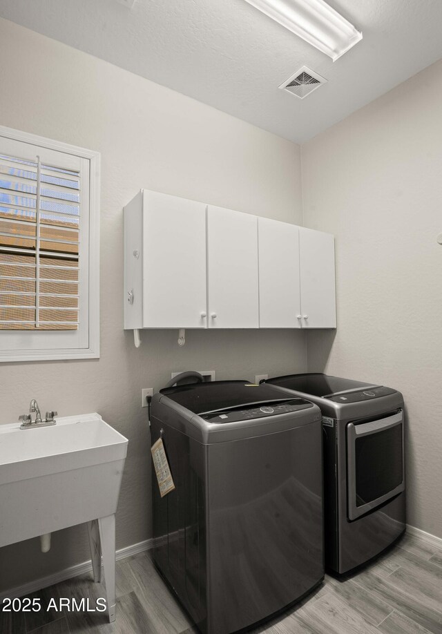 laundry area with cabinet space, independent washer and dryer, light wood-style flooring, and baseboards