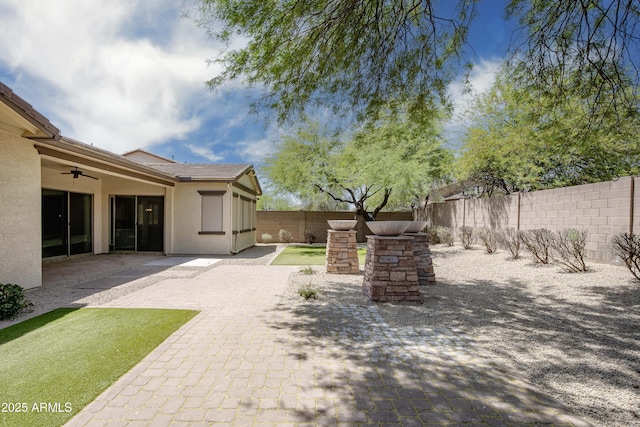 fenced backyard featuring ceiling fan and a patio