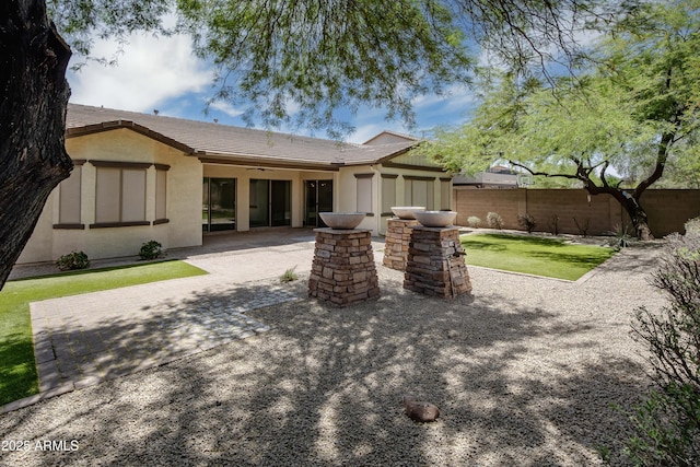 back of property featuring a ceiling fan, a patio area, stucco siding, and a tiled roof