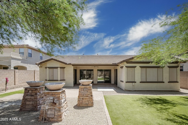 rear view of property with a tiled roof, fence, stucco siding, and a ceiling fan