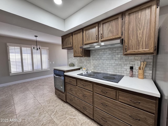 kitchen featuring hanging light fixtures, light tile patterned floors, backsplash, and black appliances