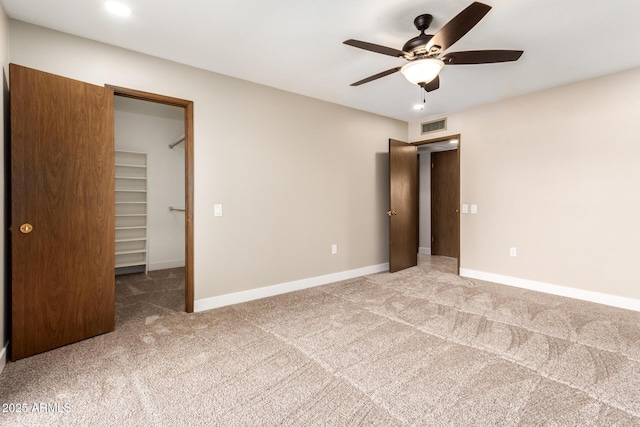 unfurnished bedroom with a closet, carpet floors, ceiling fan, and a spacious closet