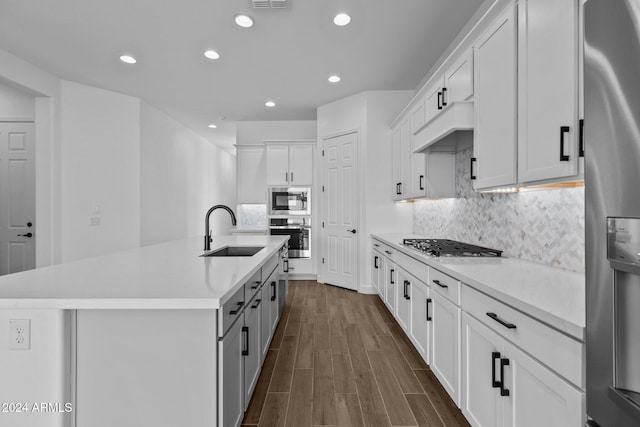 kitchen featuring appliances with stainless steel finishes, a kitchen island with sink, dark wood-type flooring, sink, and white cabinets