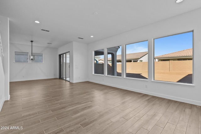 spare room with light hardwood / wood-style floors and an inviting chandelier