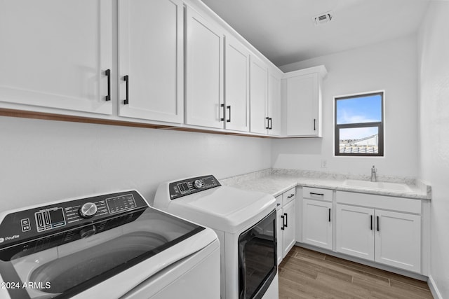 washroom with washer and dryer, light hardwood / wood-style floors, cabinets, and sink