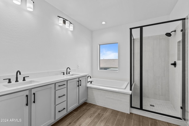 bathroom with hardwood / wood-style floors, vanity, and plus walk in shower