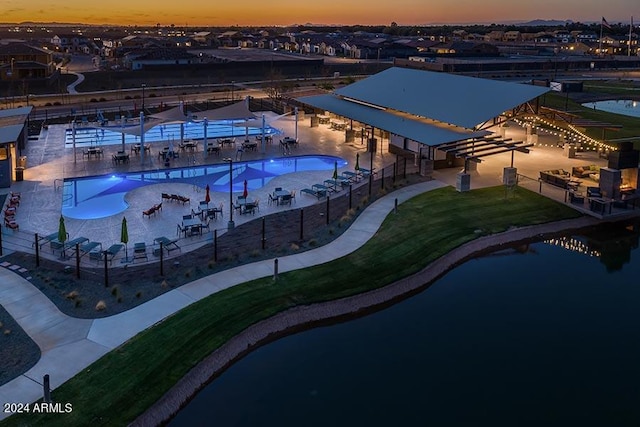 pool at dusk featuring a water view