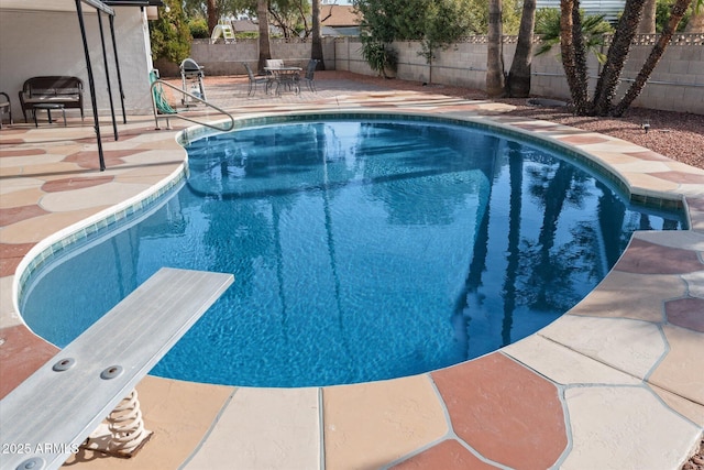 view of swimming pool featuring a diving board and a patio area