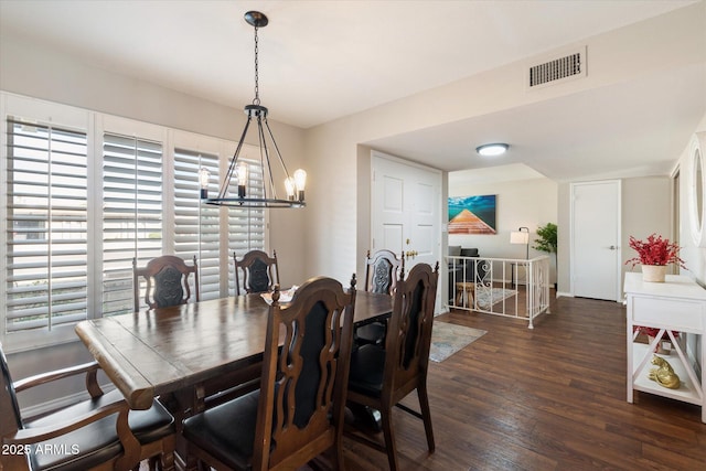 dining room with dark wood-type flooring and a notable chandelier