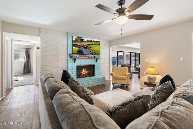 living room with a brick fireplace, hardwood / wood-style flooring, and ceiling fan