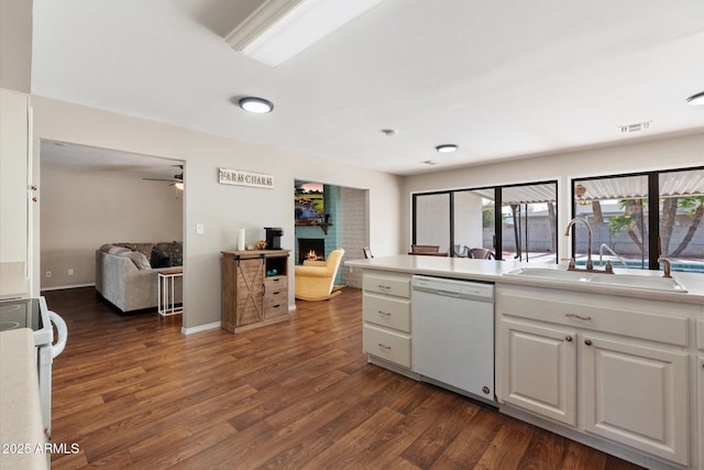 kitchen featuring dark hardwood / wood-style flooring, sink, white cabinets, white appliances, and a large fireplace