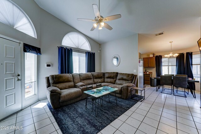 living area featuring light tile patterned floors, high vaulted ceiling, ceiling fan with notable chandelier, and visible vents