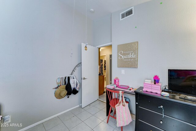 interior space with visible vents, baseboards, a towering ceiling, and light tile patterned flooring